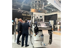 Image People standing around a machine at the tna solutions booth at Interpack 2023.
